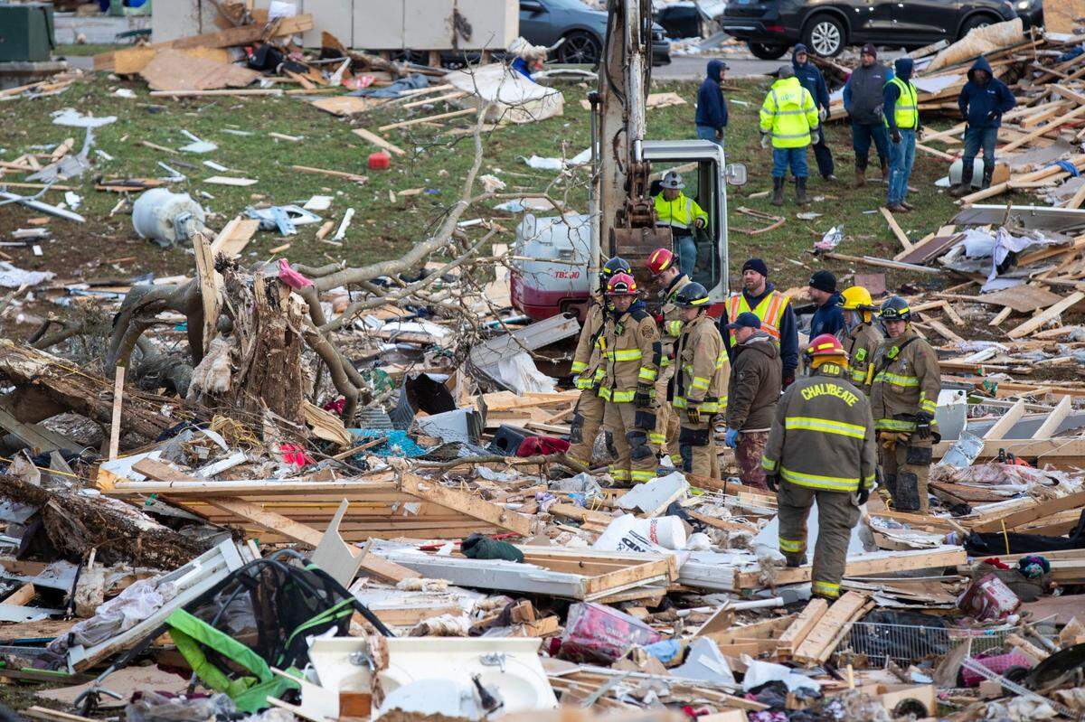Firefighters, volunteers and locals sift through debris left from houses destroyed by the tornado that came through Friday night in Bowling Green, Ky., Saturday, December 11, 2021.