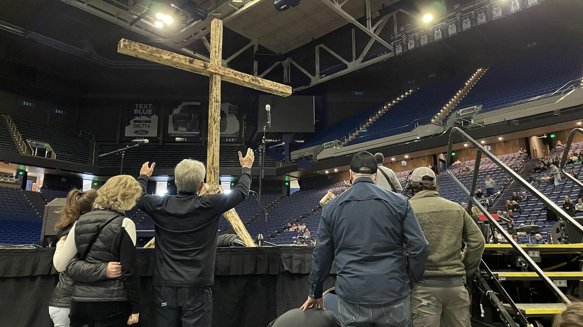 Attendees of a Christian worship event at Rupp Arena on Feb. 26, 2023, worship behind a wooden cross. 