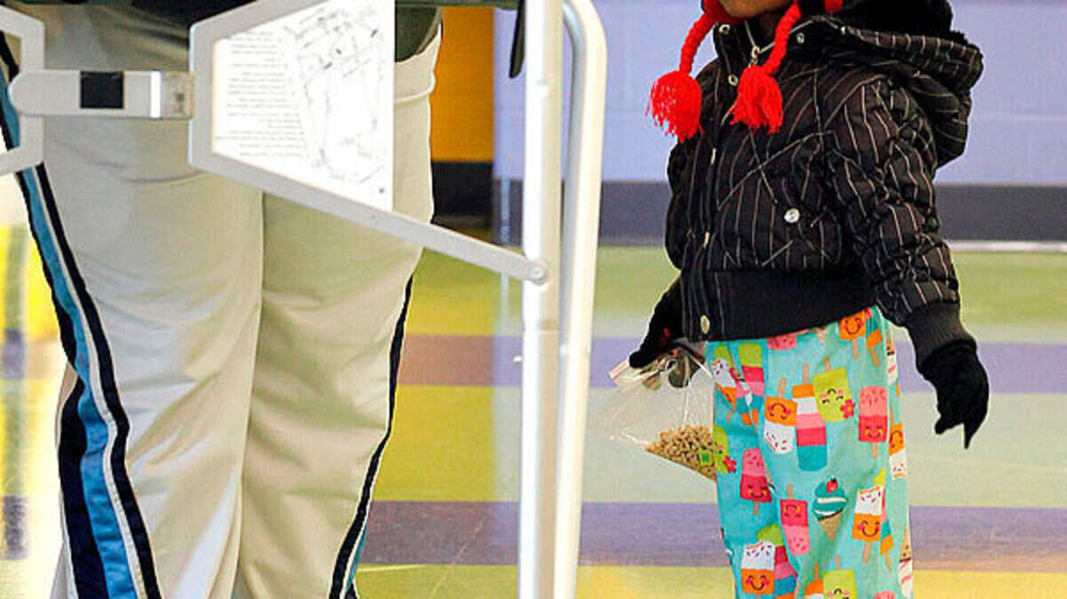 2-year-old Kadence Nicholson watched her mom, Jonisha Fondren, vote at the Aspendale Bluegrass precinct in the William Wells Brown Elementary in Lexington, Tuesday. Polls opened at 6 a.m. Kadence was holding a snack of Lucky Charms cereal.