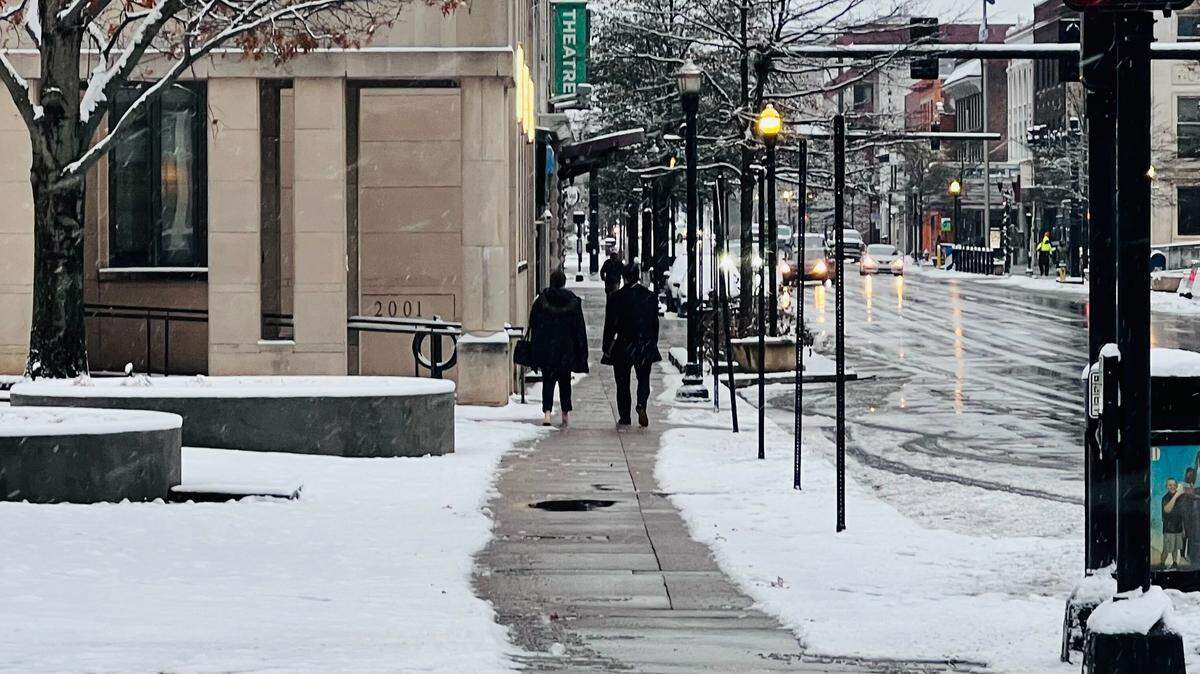People walk down East Main Street after an overnight storm dropped a few inches of snow in Lexington, Ky. on Dec. 12, 2025.