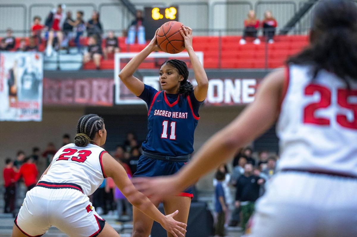 Sacred Heart’s ZaKiyah Johnson (11) looks to move the ball as George Rogers Clark’s Brianna Byars (23) plays defense during a game in Winchester, Ky., on Tuesday, Feb. 7, 2023.
