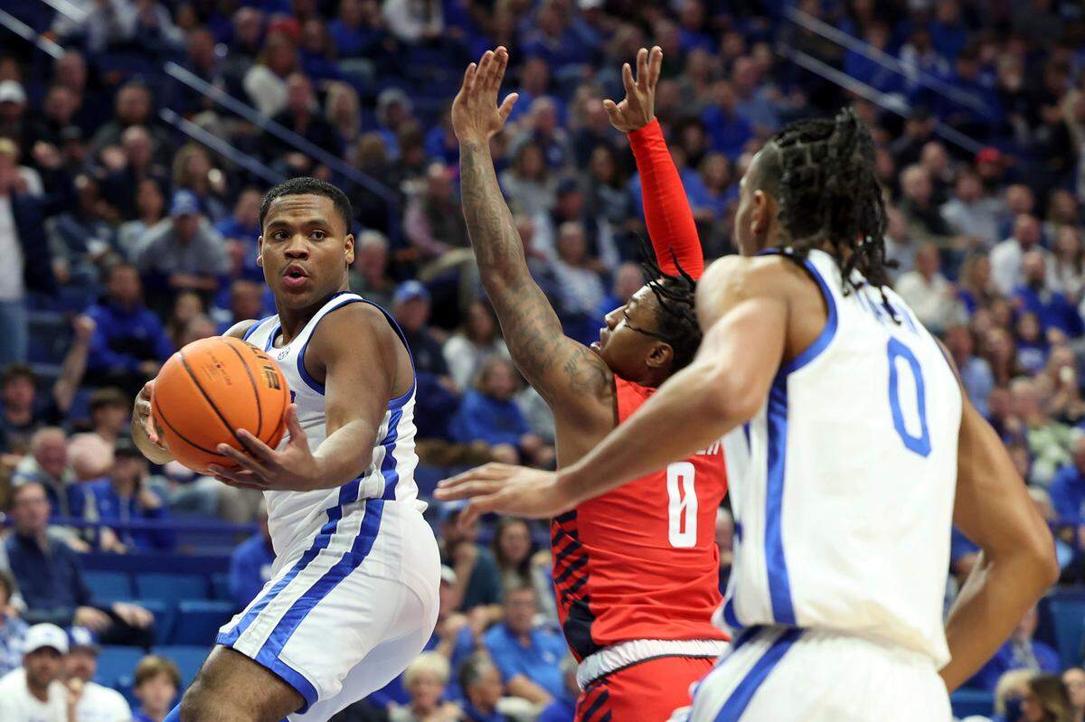 Kentucky’s Sahvir Wheeler, left, passes to teammate Jacob Toppin, right, around Duquesne’s Tevin Brewer, center, during the first half of an NCAA college basketball game in Lexington, Ky., Friday, Nov. 11, 2022.