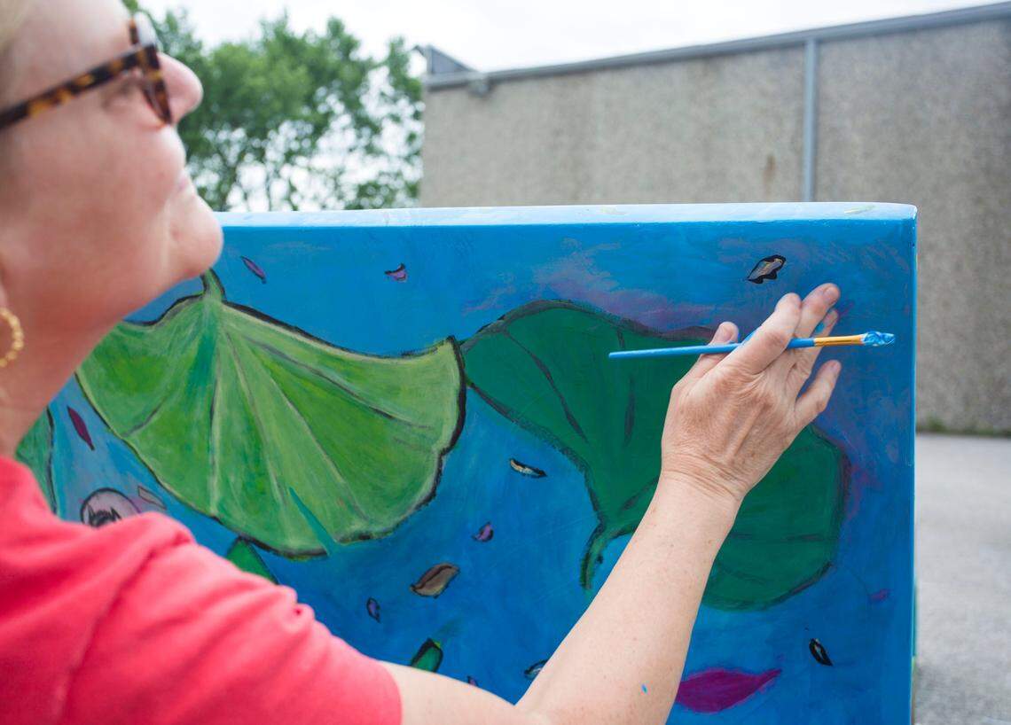 Anne Allen touches up the bench she worked on with students from the Sayre Middle School on Tuesday. "I love public art projects, because kids have a chance to have their voice heard," Allen said. 