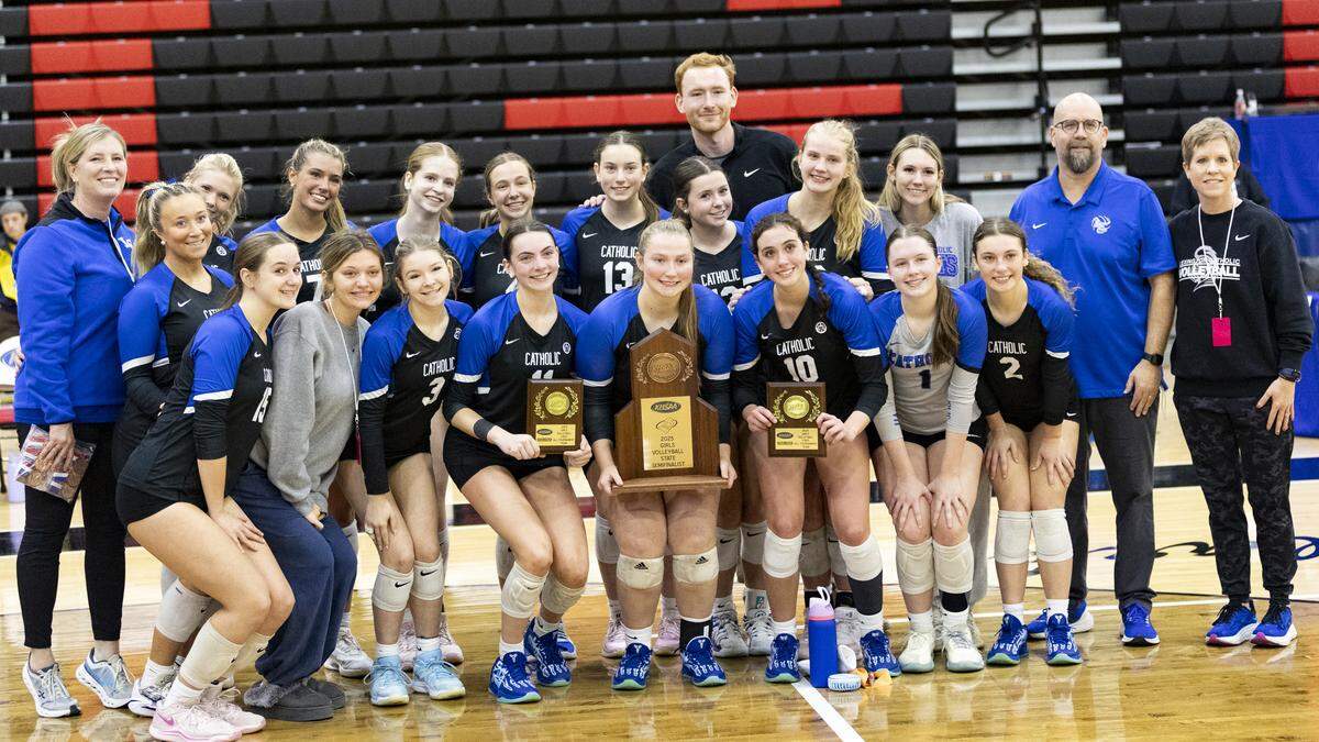 Lexington Catholic, led by head coach Jeff Kaufmann, second from right, and senior hitters and all-tournament honorees Ella Blackburn (11) and Payton Avilez (10) pose with their semifinalist trophy after the Knights’ 3-0 loss to Assumption on Saturday.