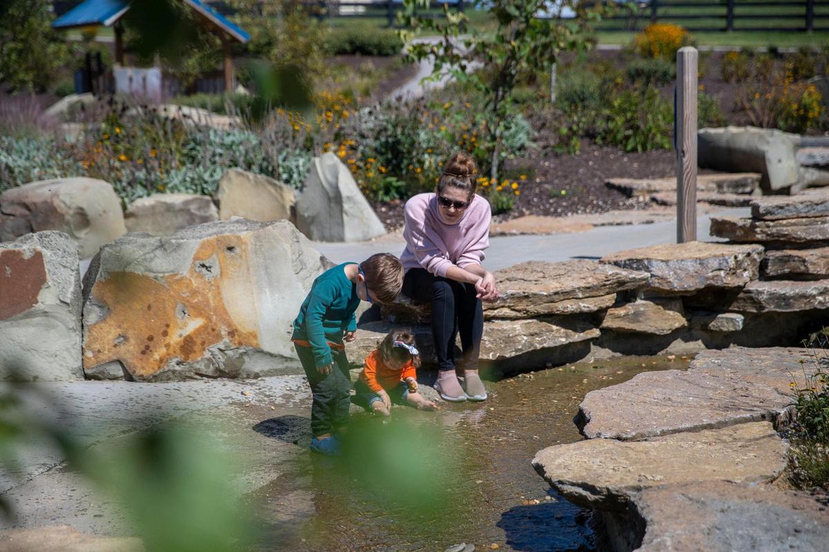 Oliver, 2, along with his sister, Belle, 8 months, and his mother, Marcie Mazzetti, explore Exploration Creek at Legacy Grove Park in Winchester, Ky., on Friday, Sept. 24, 2021.