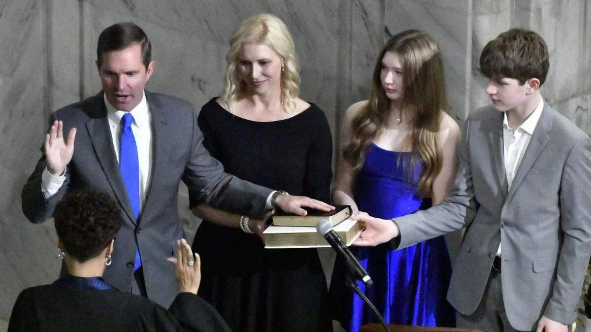 From left, Kentucky Gov. Andy Beshear, his wife, Britainy Beshear, his daughter Lila and his son Will stand by his side as he takes the oath of office from Kentucky Court of Appeals Judge Pamela Goodwine during his inauguration in Frankfort, Ky., early Tuesday, Dec. 12, 2023. (AP Photo/Timothy D. Easley)