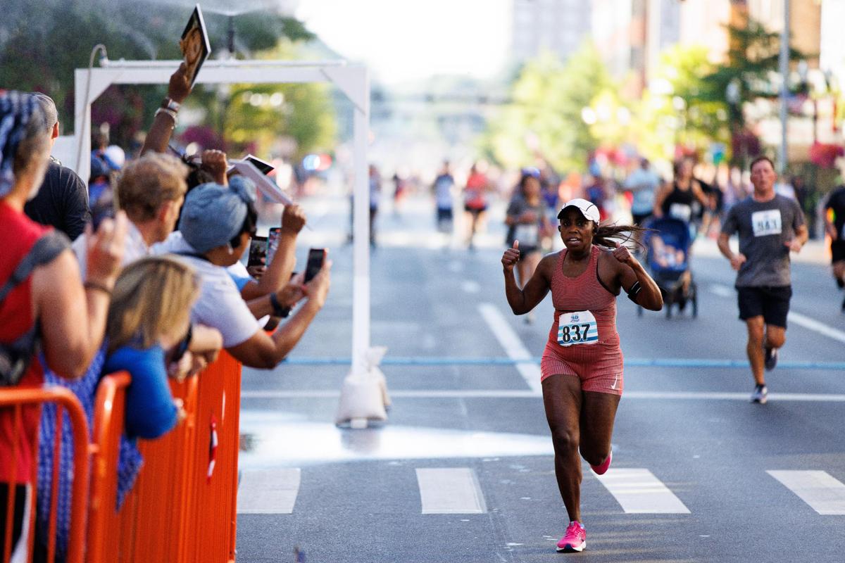 Phillina Wingate is cheered on by friends and family as she crosses the finish line in the Bluegrass 10,000.
