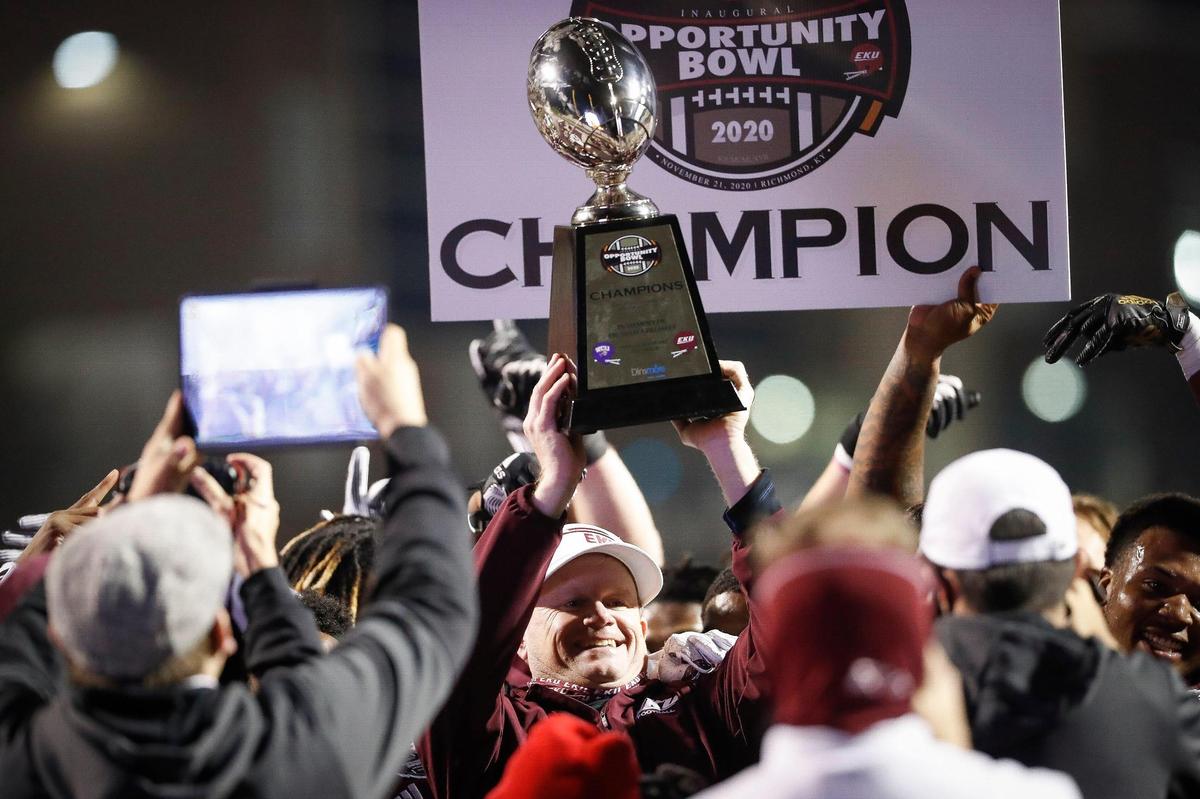 First-year Eastern Kentucky head coach Walt Wells hoisted the Opportunity Bowl trophy while celebrating Saturday’s win over Western Carolina with his Colonels in Richmond.