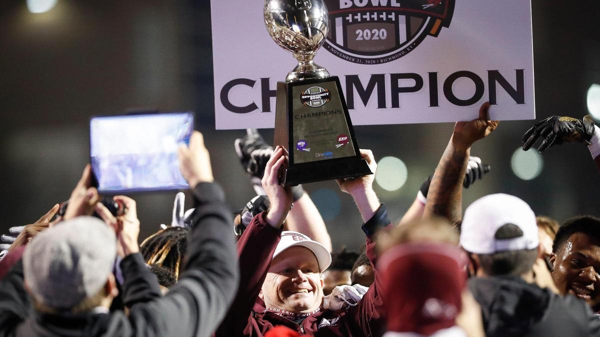 Eastern Kentucky Colonels football coach Walt Wells hoisted the trophy while celebrating with the team after the Colonels defeated Western Carolina 49-17 last year in the Opportunity Bowl.