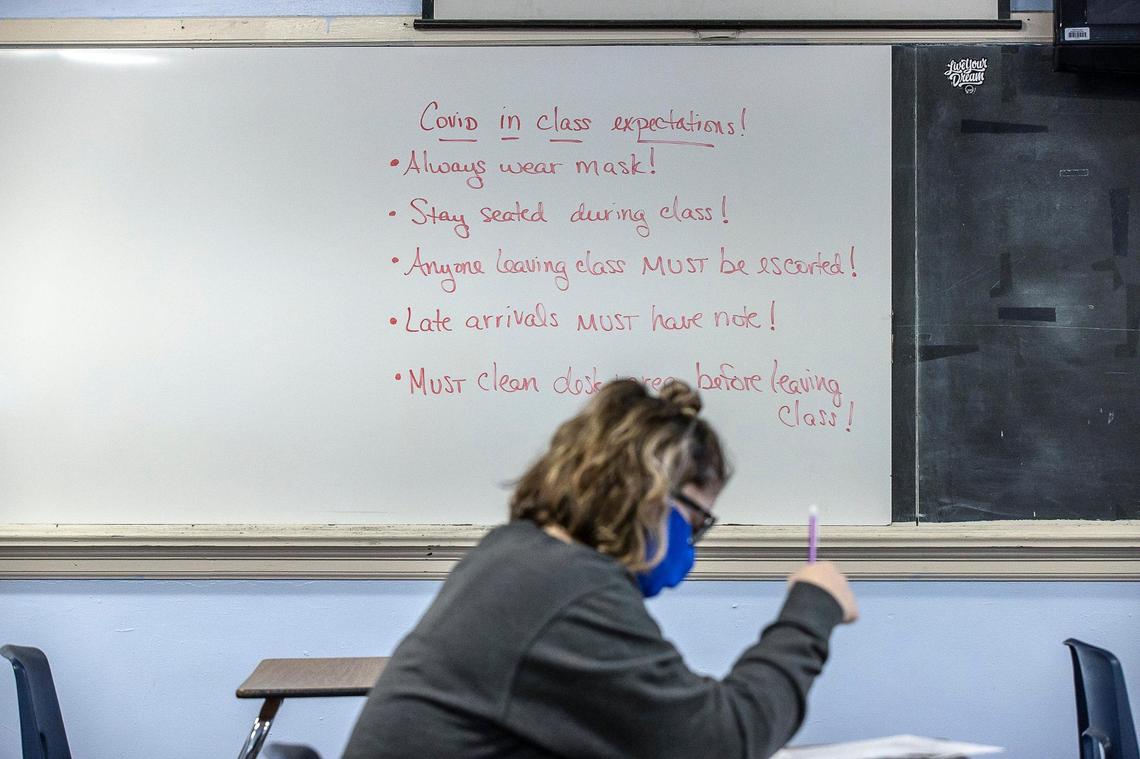 Class expectations to help reduce the spread of COVID-19 are written on a whiteboard in a classroom at Frankfort High School in Frankfort, Ky., as Macy Dungan, a senior, takes a math test.