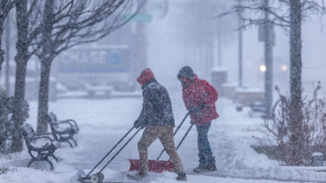People clear snow from a sidewalk in downtown Lexington, Ky., on Sunday, Jan. 5, 2025.