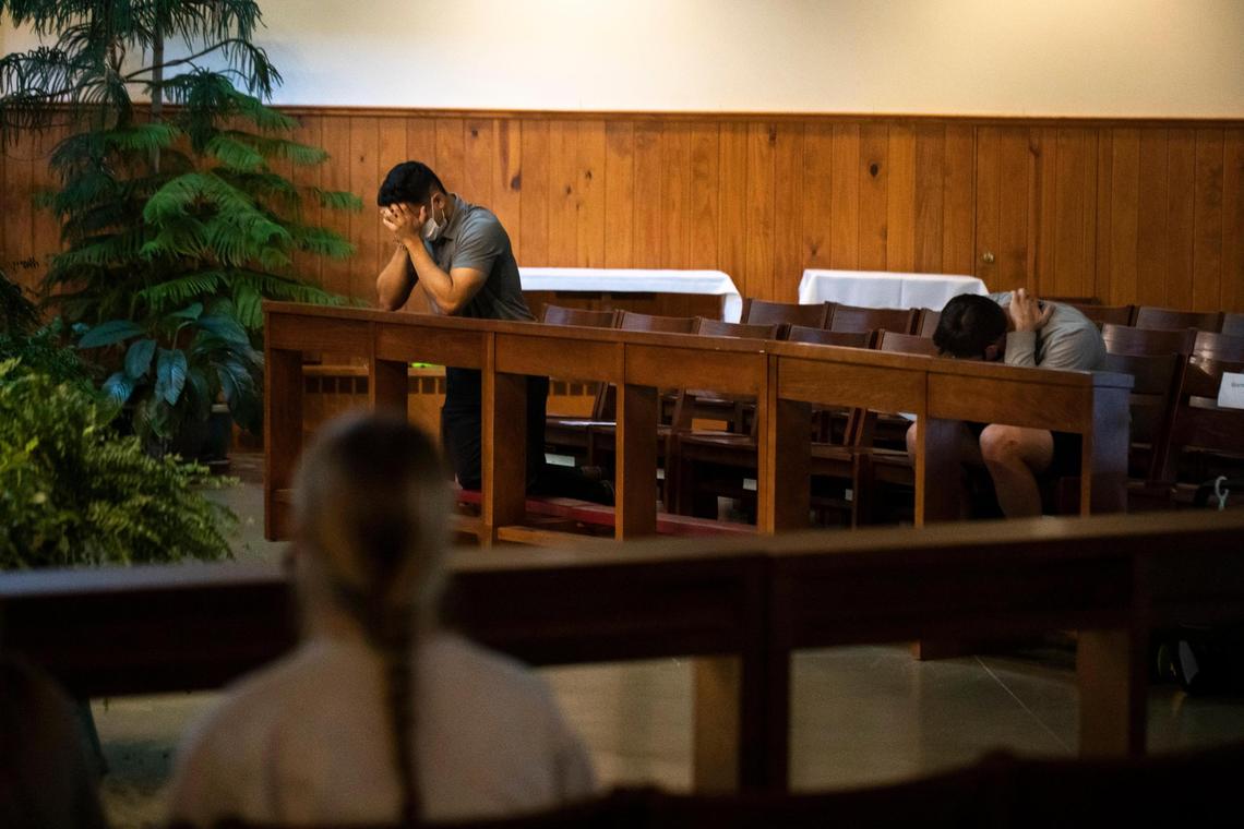 People bow their heads while gathering at the Holy Spirit Parish Catholic Newman Center for a campus prayer vigil and mass for Thomas Lofton Hazelwood, who died Monday night after being found at the frat house in Lexington, Ky., Thursday, October 21, 2021.