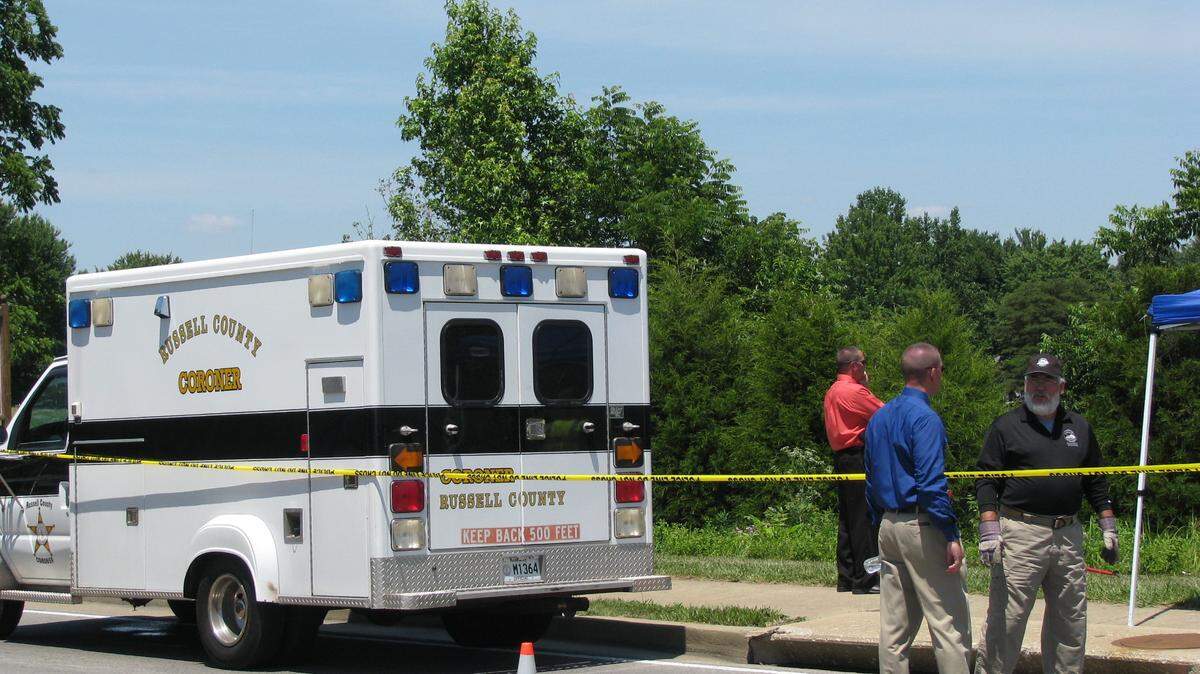 A coroner's vehicle stood by as authorities searched the scene where a 31-year-old Russell County woman's body was found Thursday. Sarah Hart was found among the trees at the back of the photo. 6/14/2012 photo by Bill Estep