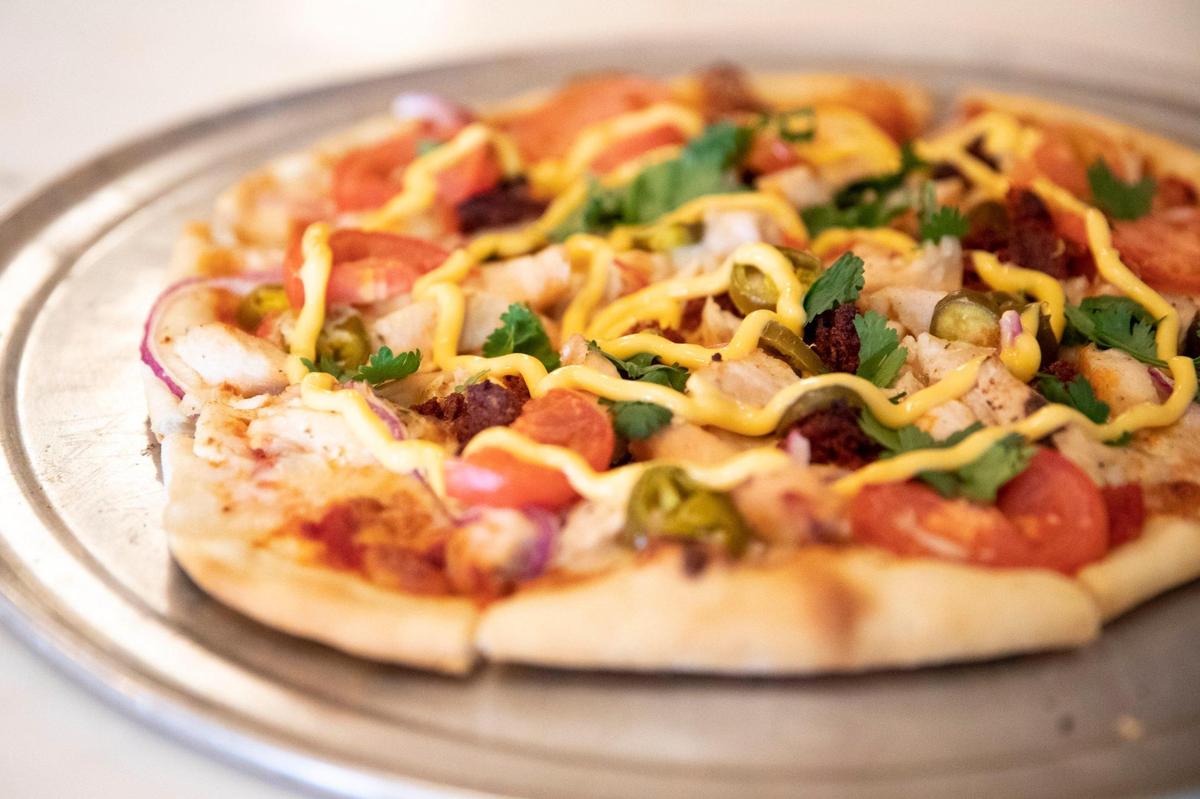 The Down and Out pizza, including marina, mozzarella, chicken, chorizo, tomato, onion and jalape–o, topped with cheddar cheese sauce and cilantro, at the Engine House Pub and Pizza Parlour.