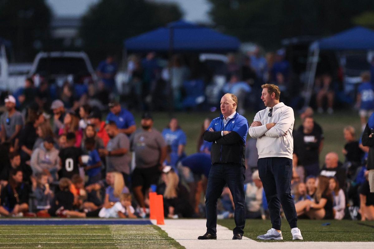Kentucky football head coach Mark Stoops and offensive coordinator Liam Coen talk on the sideline while watching Lexington Christian host Lexington Catholic on Friday night.