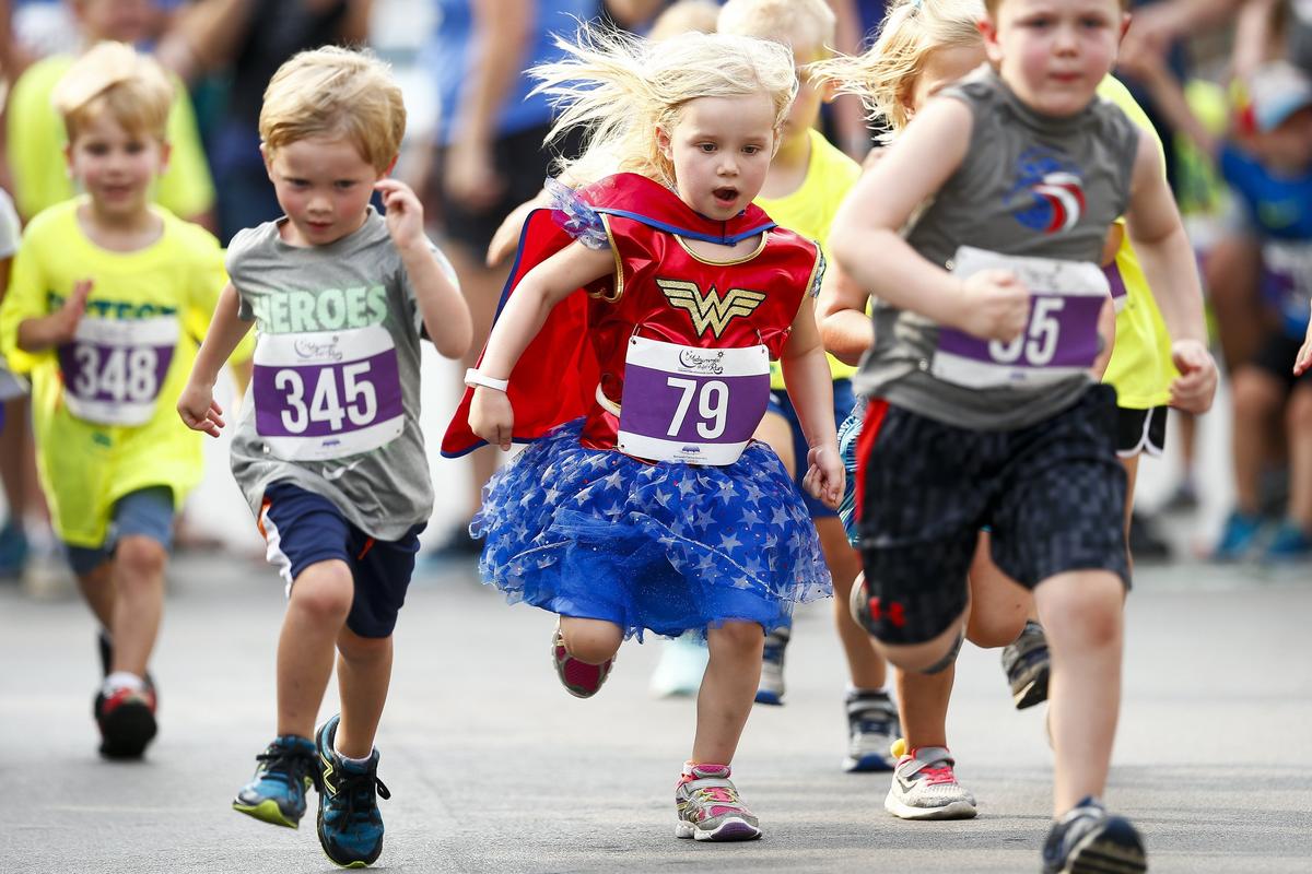 Caroline Pickett, 4, of Lexington, center, competed in a Wonder Woman costume during the four-year-old heat of the Fastest Kid in Town competition Saturday in downtown Lexington.