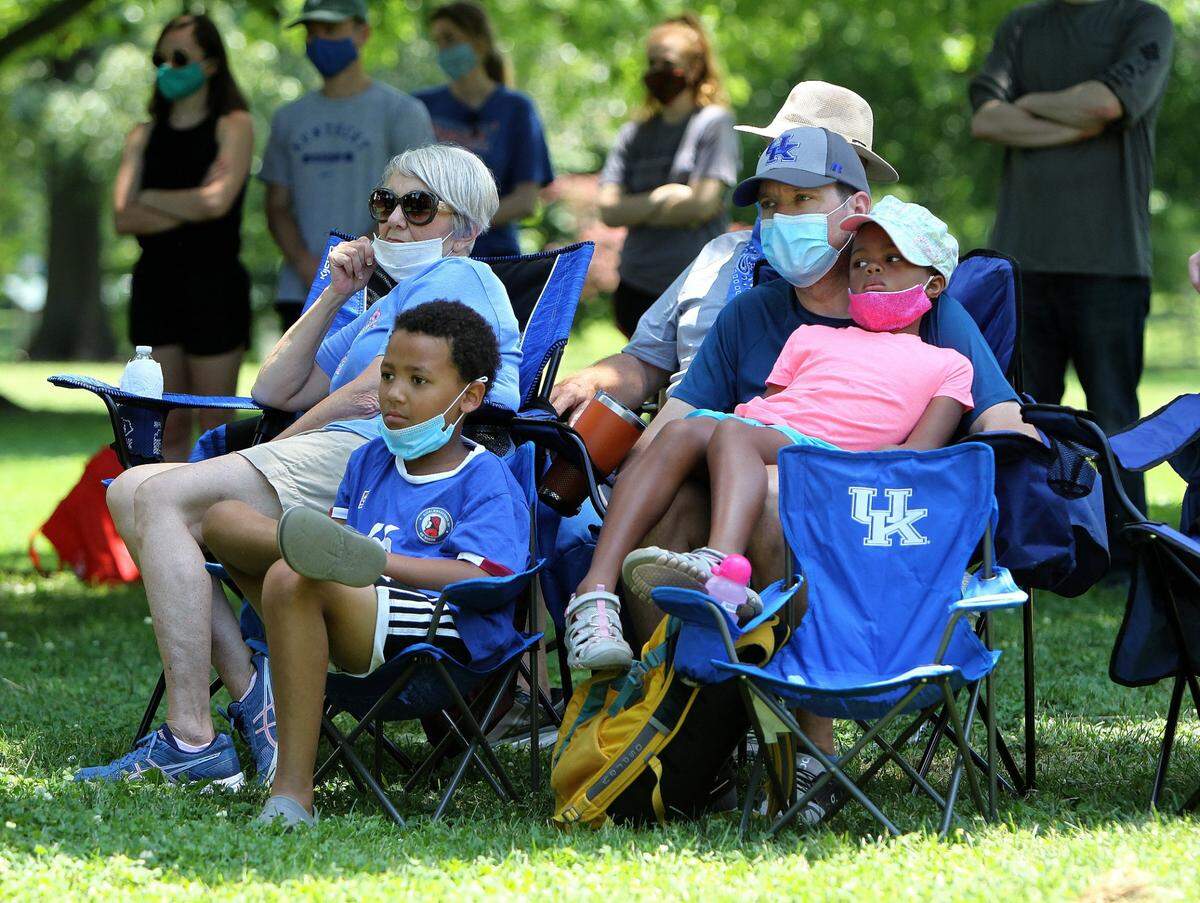 Erik Ballert held daughter Marissa, 7, as son Quay, 8, and the children’s grandmother, Lori Richardson, listened to a speaker Saturday afternoon during the Walk Forward Lexington rally at Woodland Park.