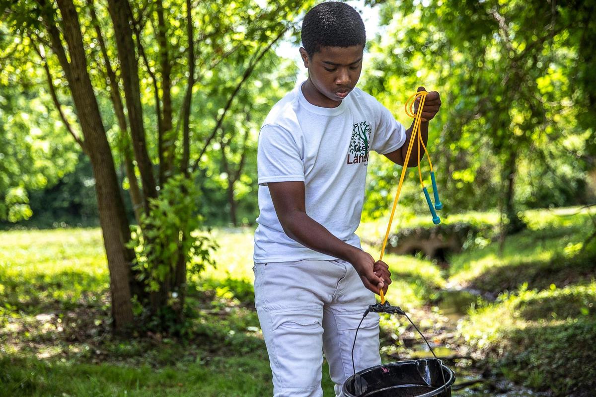 Jacory Curtis hauls in water from a creek near his gardening plot at GreeneLanding. When the challenge ends, cooperative extension experts from UK and KSU will decide who produced the best vegetable.