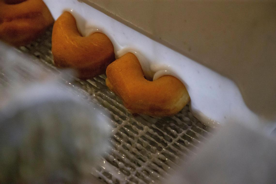 Donuts make their ways through the glazing process Wednesday at Donut Days Bakery in Lexington. The bakery is preparing for an influx of customers on Friday in celebration of National Doughnut Day and owner Fred Wohlstein says glazed donuts will likely be the most popular variety.