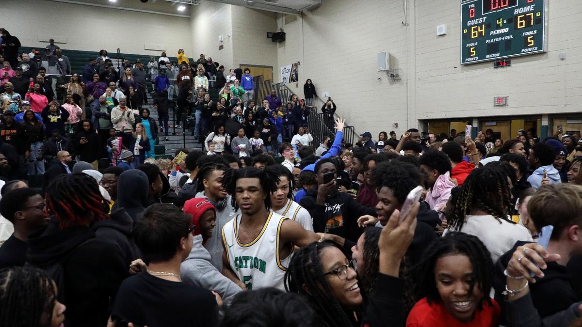 Bryan Station’s Amari Owens (5) celebrates as fans storm the court after the Defenders beat Frederick Douglass at Bryan Station High School on Friday.