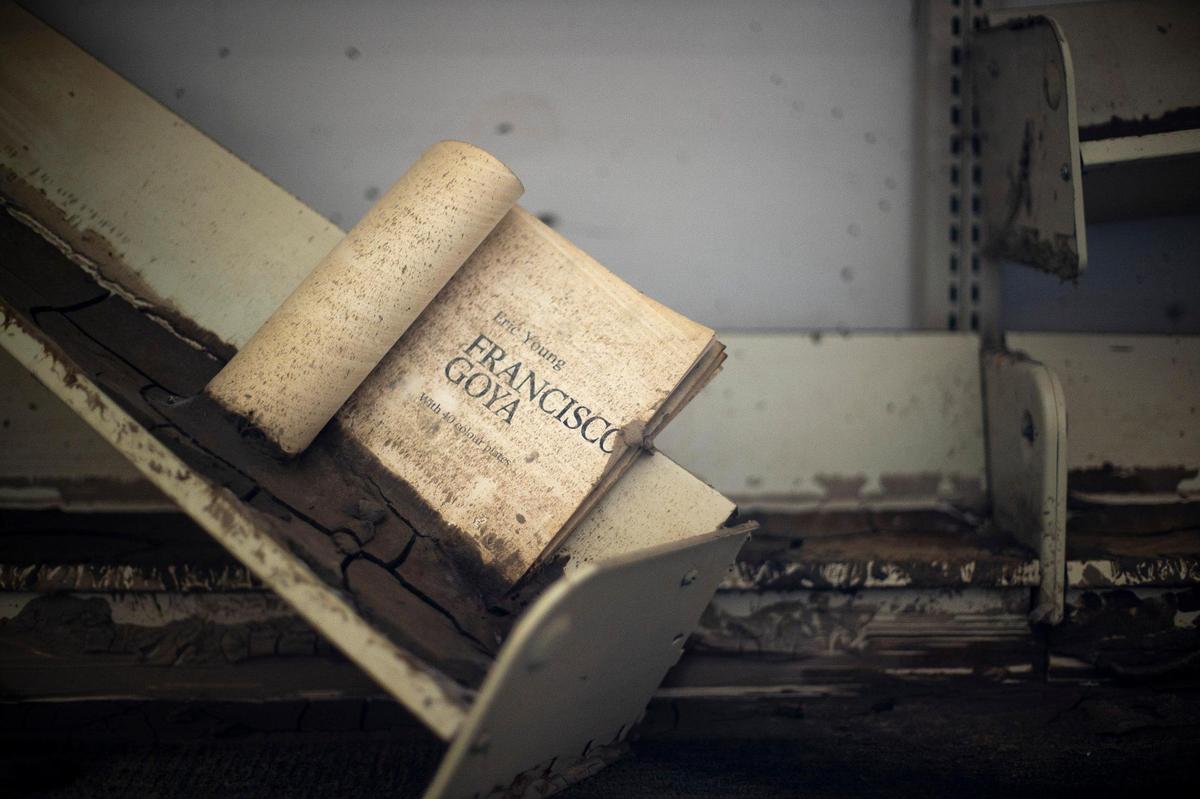 A book, stuck in mud, rests on a broken shelf at the Fleming-Neon Public Library in Fleming-Neon, Ky., on Wednesday, Aug. 31, 2022. The library was damaged by flooding in late July.