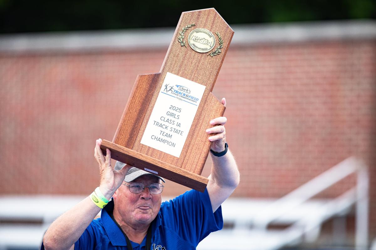 Lexington Christian assistant coach Ray Hayes joins a victory lap with the state championship trophy.