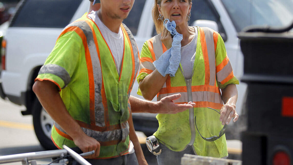 Besides dealing with a high heat index, Jason Caldwell Jr. and Kyla Gerkey handled a "thermo cart" that produced 450-degree heat to install traffic stripes Thursday on Midland Avenue. It takes the high temperature for the plastic to bond to the blacktop.     