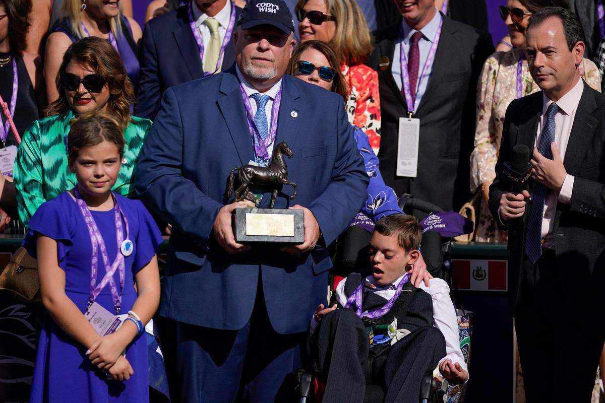 Cody Dorman, center below right, sits alongside his father Kelly Dorman, left holding trophy, mother Leslie Dorman, second from left, behind, and sister Kylie, left, after jockey Junior Alvarado rode Cody’s Wish to win the Breeders’ Cup Dirt Mile horse race Saturday, Nov. 4, 2023, at Santa Anita Park in Arcadia, Calif. Cody’s Wish is named after Cody Dorman. (AP Photo/Ashley Landis)