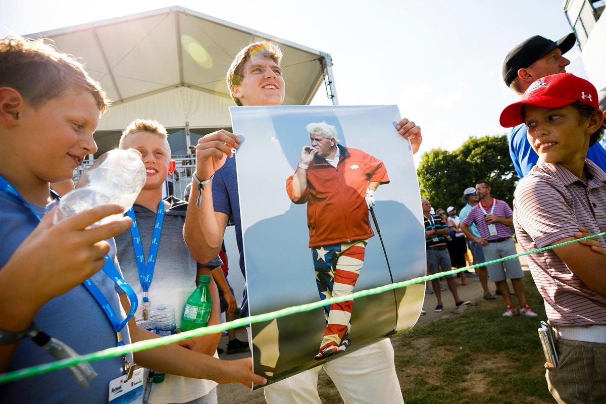 Ryan Stucky of Lexington holds a poster of John Daly as Daly putts on No. 18 on Friday. Daly shot 71, 72 to finish at 1-under par for the tournament and miss the cut.