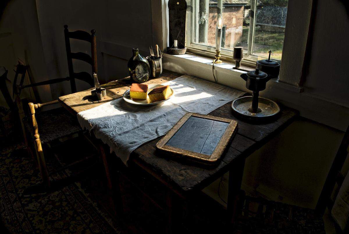 Slave quarters and table with the ansion seen through rainy window. Although it was against Kentucky law, the slaves at Waveland were taught to read and write. And were allowed to attend church together, although sitting in the balcony.
