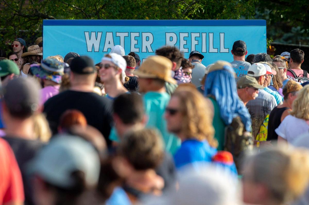 People wait in line to get water at a water refill station at the Railbird Festival at Keeneland in Lexington, Ky., on Saturday, Aug. 28, 2021.