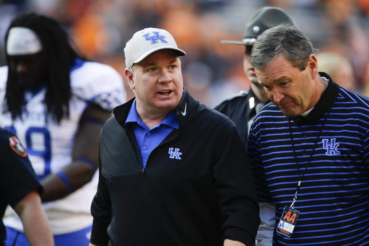 By terms of the contract negotiated by Kentucky athletics director Mitch Barnhart, right, UK football coach Mark Stoops, left, would receive a buyout of almost $38 million within 60 days of termination if the university fired him without cause this season. 
