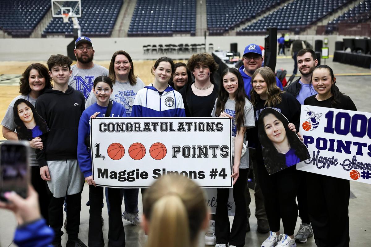 Nicholas County freshman Maggie Simons, center, held up one of two signs marking her 1,000th career point, which she scored against Menifee County. At right, Simons’ cousin, Katie Switzer held up another sign. Simons reached the milestone with the opening basket of the game, a 3-pointer, in the first round of the All “A” Classic at The Corbin Arena on Wednesday.