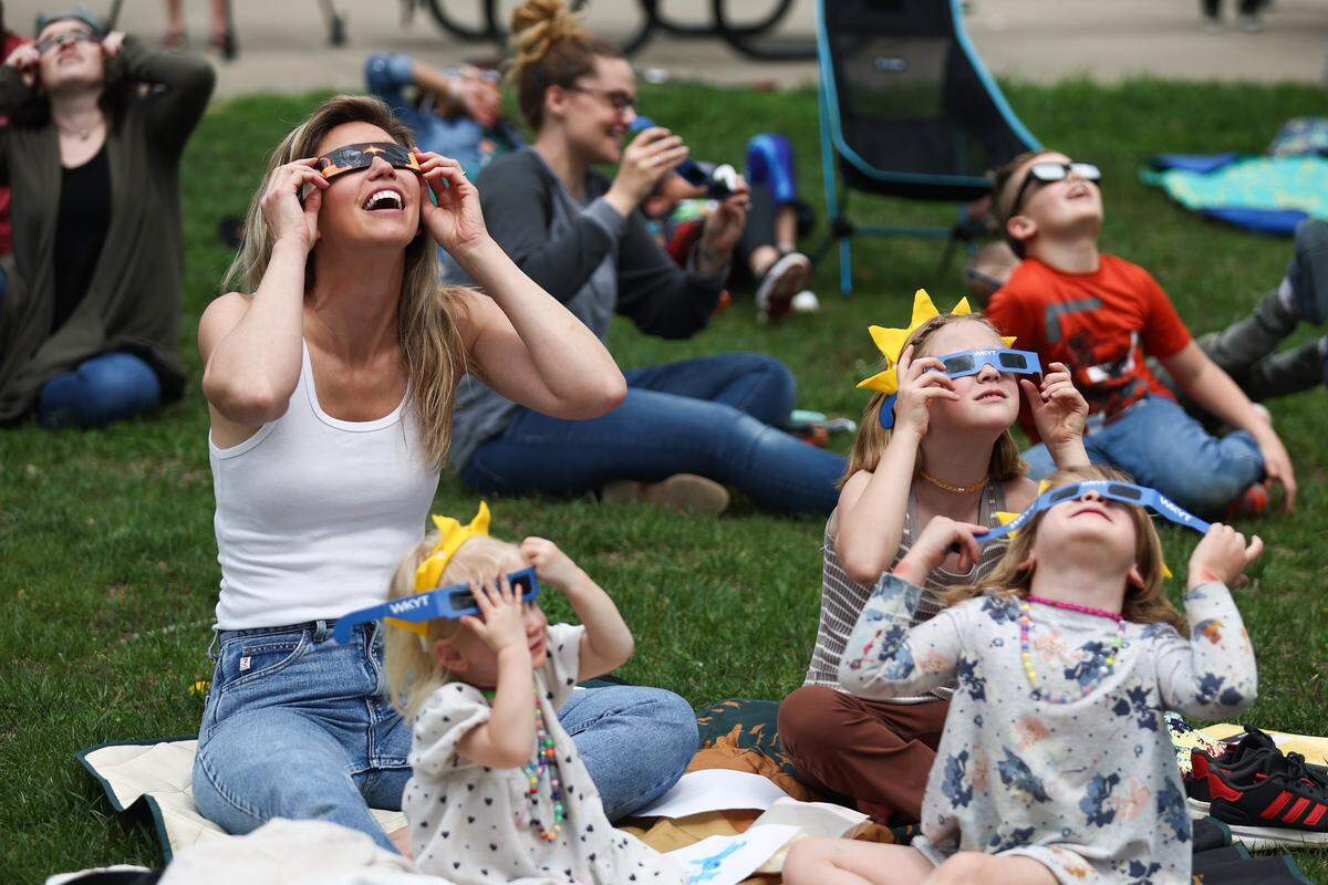 Jessica Lundgaard and her daughters Izzy, Soleil and Layla react as the eclipse emerges from cloud over at Living Arts and Science Center in Lexington, Ky., on April 8, 2024. The area was expected to see around 96% totality.