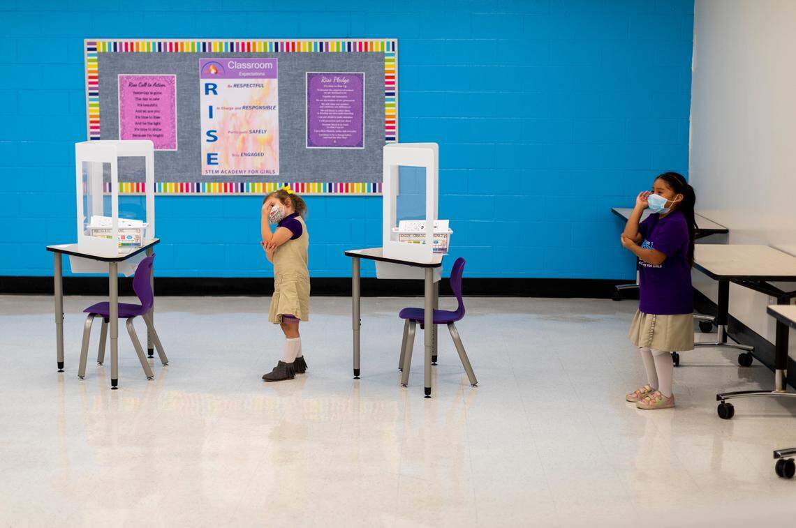 Abigail Neal (left) and Kayli Canseco-Jimenez take activity breaks behind their desks in the kindergarten classroom at the Rise Stem Academy for Girls in Lexington, Ky., Monday, October 19, 2020. Students returned to classes at the academy with a maximum of 7 students in the classroom with masks on and plastic dividers at their desks.
