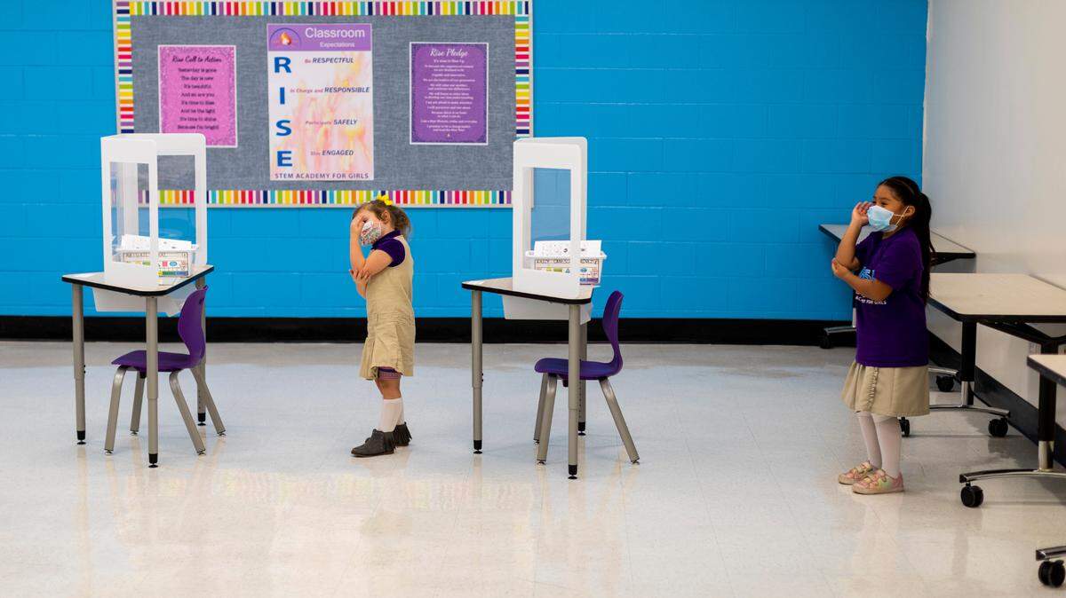 Abigail Neal (left) and Kayli Canseco-Jimenez take activity breaks behind their desks in the kindergarten classroom at the Rise Stem Academy for Girls in Lexington, Ky., Monday, October 19, 2020. Students have returned to classes at the academy with a maximum of 7 students in the classroom with masks on and plastic dividers at their desks.