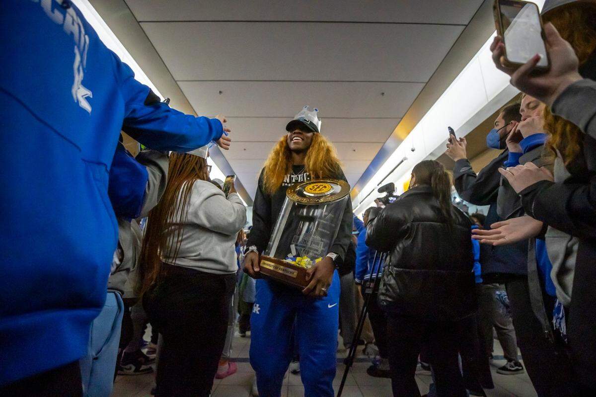 Rhyne Howard, the SEC Tournament MVP, carries the team trophy as the Kentucky squad is greeted by fans at the Joe Craft Center on the UK campus on Sunday night.