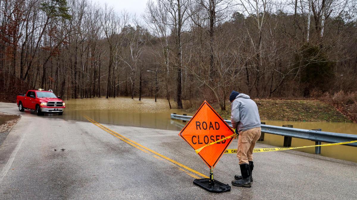 Beattyville City employee Wallace Todd moves up the road closed sign on Silver Creek Road, Sunday, Feb. 14, 2025, as the water level kept rising after severe overnight rain hit the Eastern Kentucky town of Beattyville, Ky.