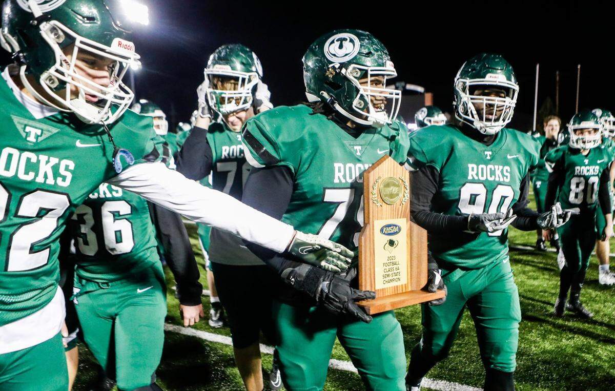 Trinity’s Claude Mahan carries the Class 6A semifinal trophy after the Shamrocks defeated Frederick Douglass 14-7 in overtime in Louisville on Friday night. Trinity will face Bryan Station for the state championship.