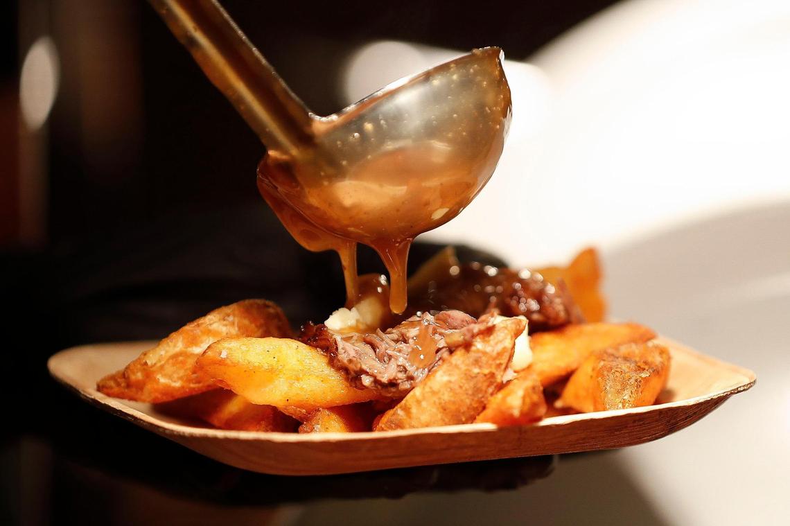 Joe Mullins, of Lexington, Ky., pours a ladle of gravy over a plate of wedge fries and bourbon braised short ribs In the new VIP Club at Rupp Arena Aug. 18, 2021.