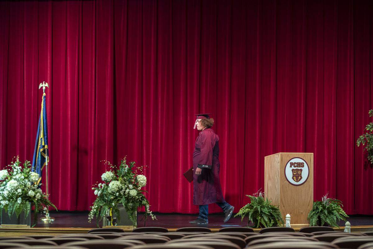 Johnny Hensley walks across the stage in a nearly empty auditorium May 20. Video clips of students were taken and compiled into a graduation video that later was shown at a drive-in theater.
