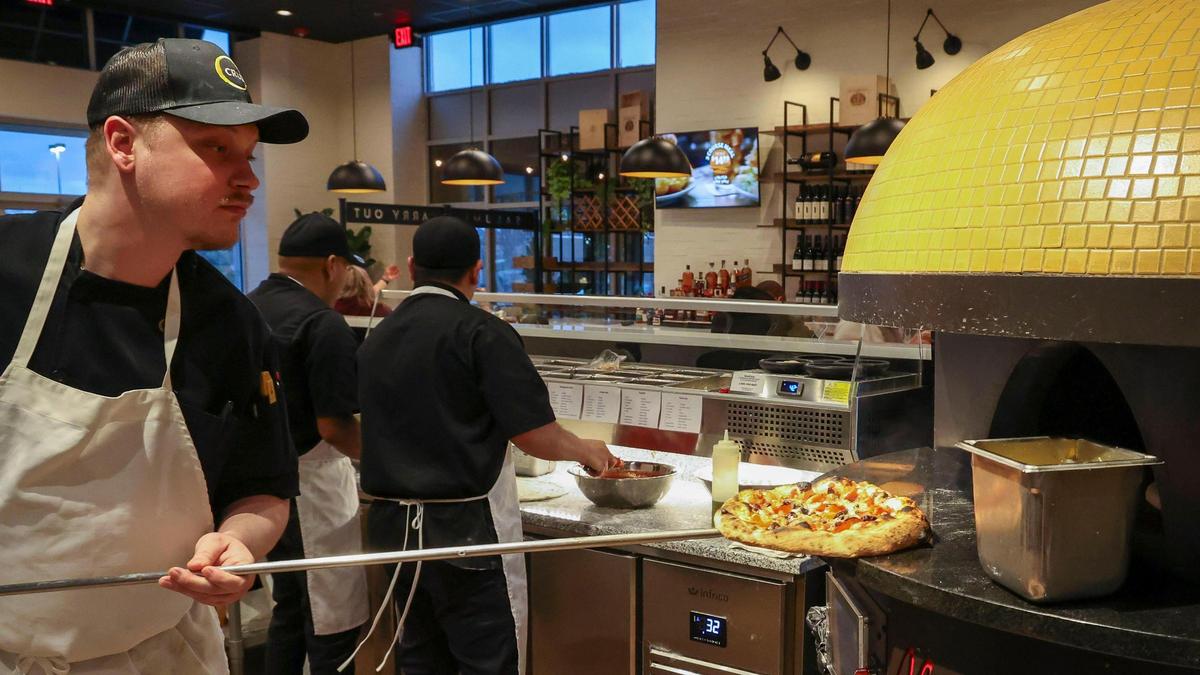 Crust Assistant General Manager Travis Taulbee pulls a Nemesis pizza out of the Italian stone oven, Thursday, March 20, 2025 at the Lexington, Ky. pizzeria. The Nemesis ($19) is topped with ‘nduja spreadable pork, fior di latte cheese, peppadew peppers and fresh basil.