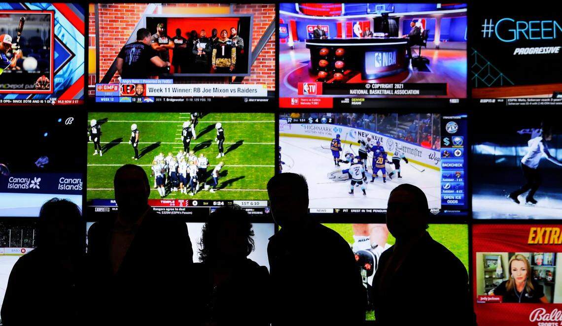 A group of people stand in front of a wall of televisions showing a variety of sports during the opening event for Oneida Casino’s sports betting operation on Nov. 30, 2021, in Ashwaubenon, Wis. Gpg Oneidasportsbetting 113021 Sk26