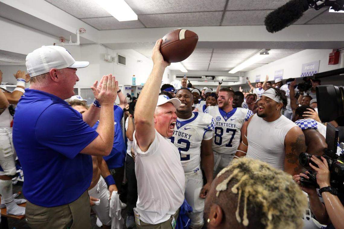 John Schlarman, with game ball, reveled in a Kentucky victory inside the UK locker room. “Kentucky football won’t be the same without him but his legacy will never fade,” head coach Mark Stoops, left, said. “He was a fighter and we will strive every day to honor his warrior spirit.”