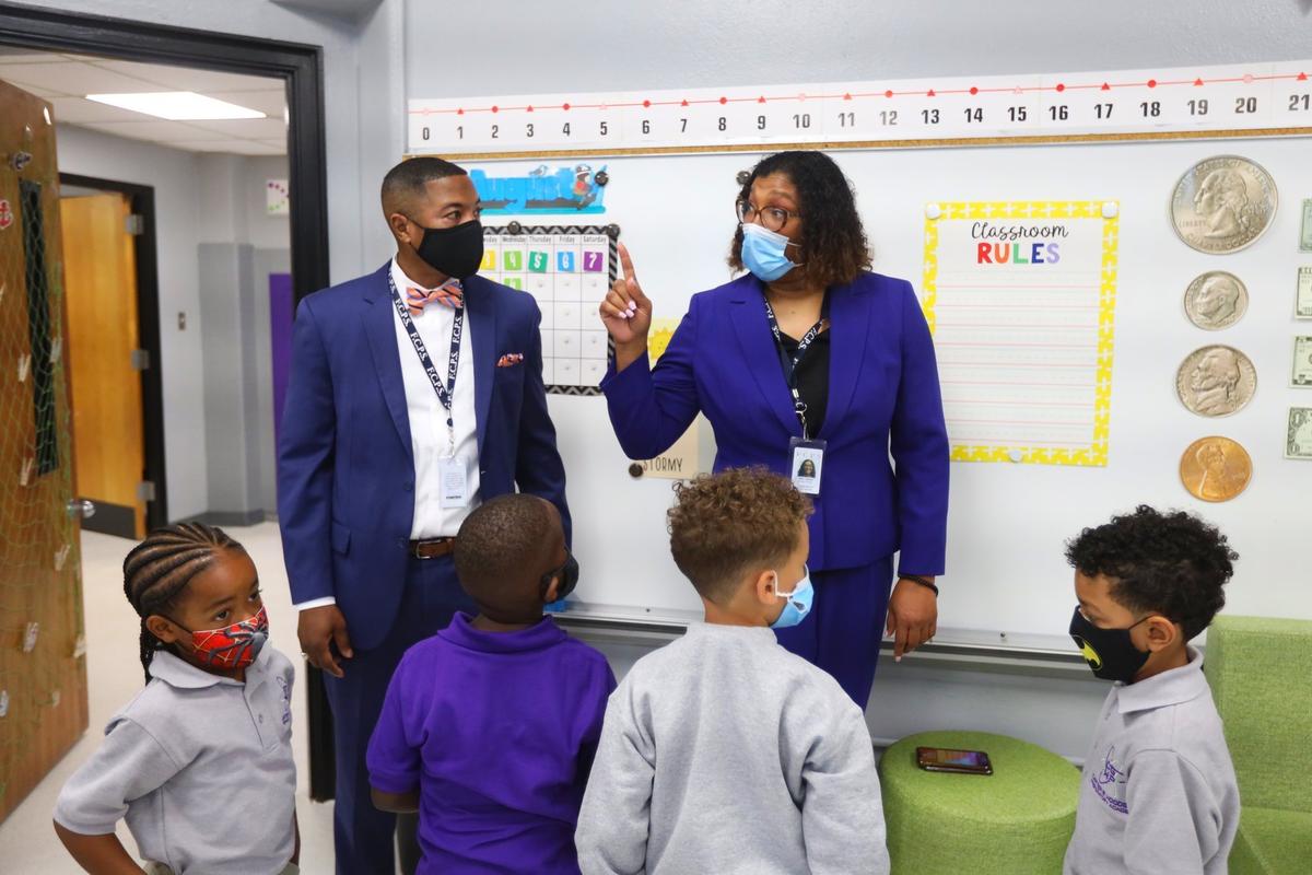 Superintendent Demetrus Liggins, left, listened as Carter G Woodson Academy program director Jocelyn Mills, right, directs first-graders' attentions on their first day of class Wednesday.