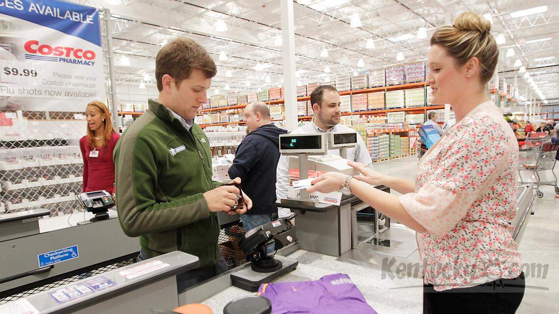 Christina Carneal, right, helped customers Chase Eldridge, left and Michael Bedrick, center, during a grand opening at Costco in Lexington, Ky., on Oct. 18, 2013. Photo by Pablo Alcala | Staff 