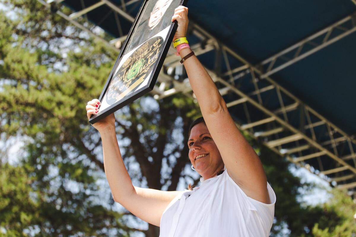 Director Tiffany Finley held up a poster honoring John Prine at the Master Musician’s Festival 2018. Prine, who died of COVID in 2020, headlined that year, his last major regional performance.