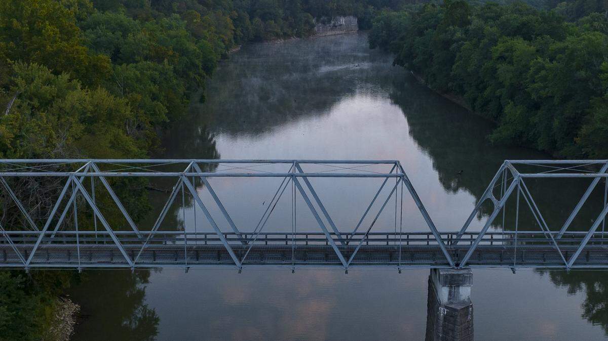 The sun rises over the Old Clay’s Ferry Bridge crossing the Kentucky River at the Fayette and Madison county line, Sept. 19, 2023.