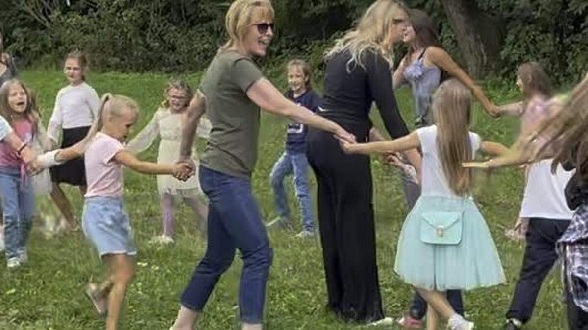 Joan Root of Lexington, wearing sunglasses, has been volunteering in the Ukraine to help families displaced by the war. She dances with children in 2023 after feeding Ukrainian families pizza as part of an international volunteer effort.