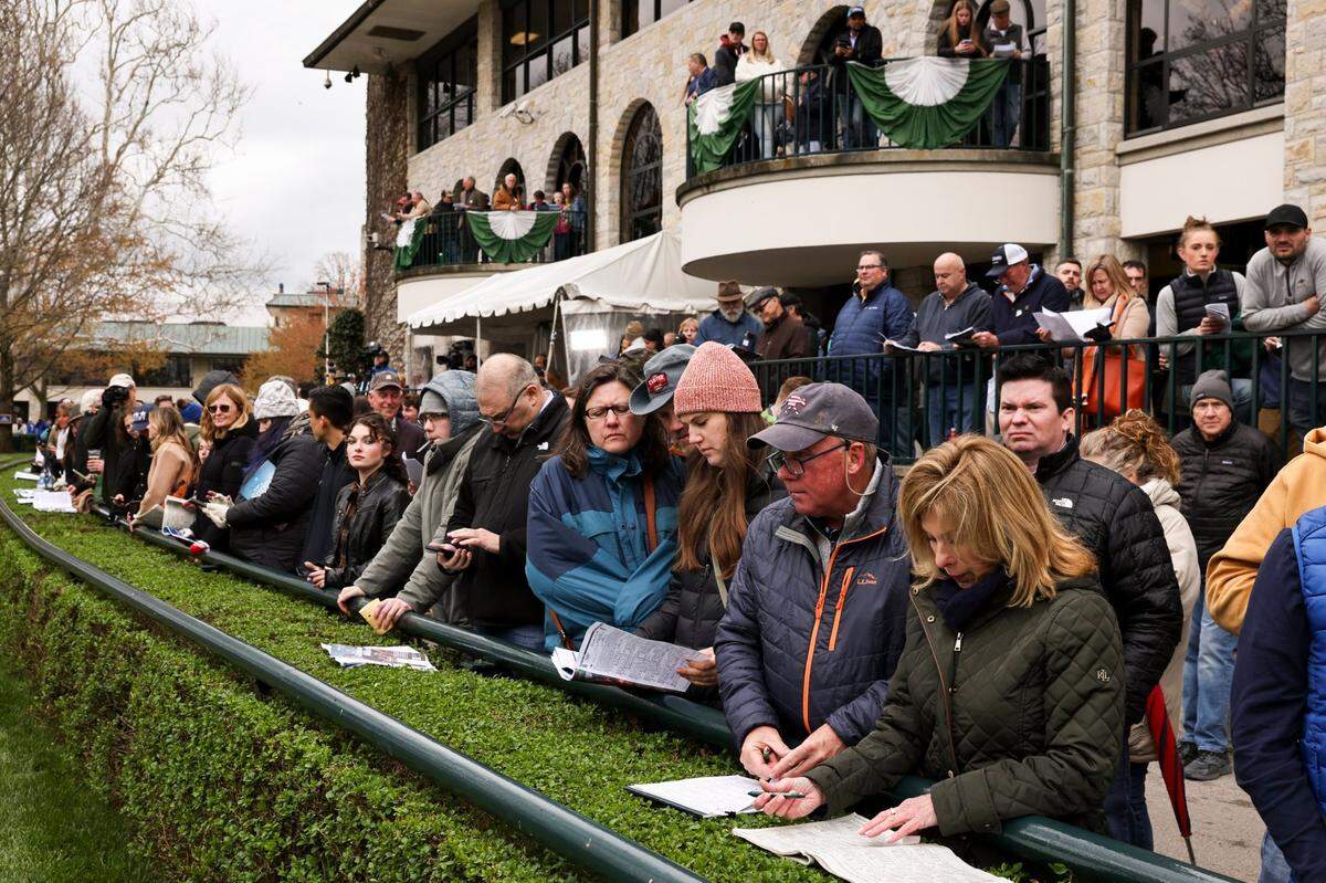 Patrons consult and observe horses in the paddock during the opening day of the Keeneland Spring Meet in 2024.